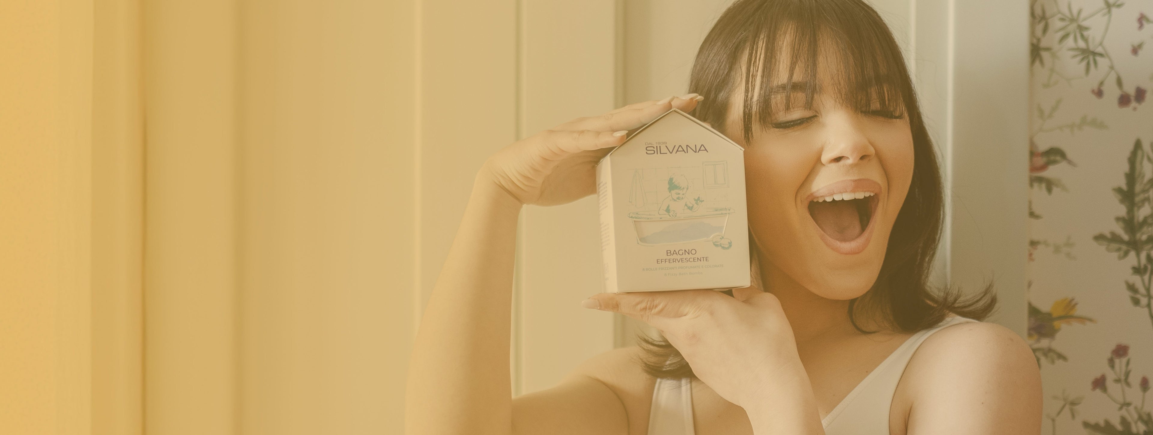 Donna sorride tenendo Bagno Effervescente Silvana, cosmetico naturale bambini, per pelli sensibili, Made in Italy