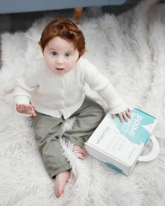 Bambino su tappeto con confezione Silvana Primi Bagnetti, cosmetici naturali bambini per pelli sensibili Made in Italy