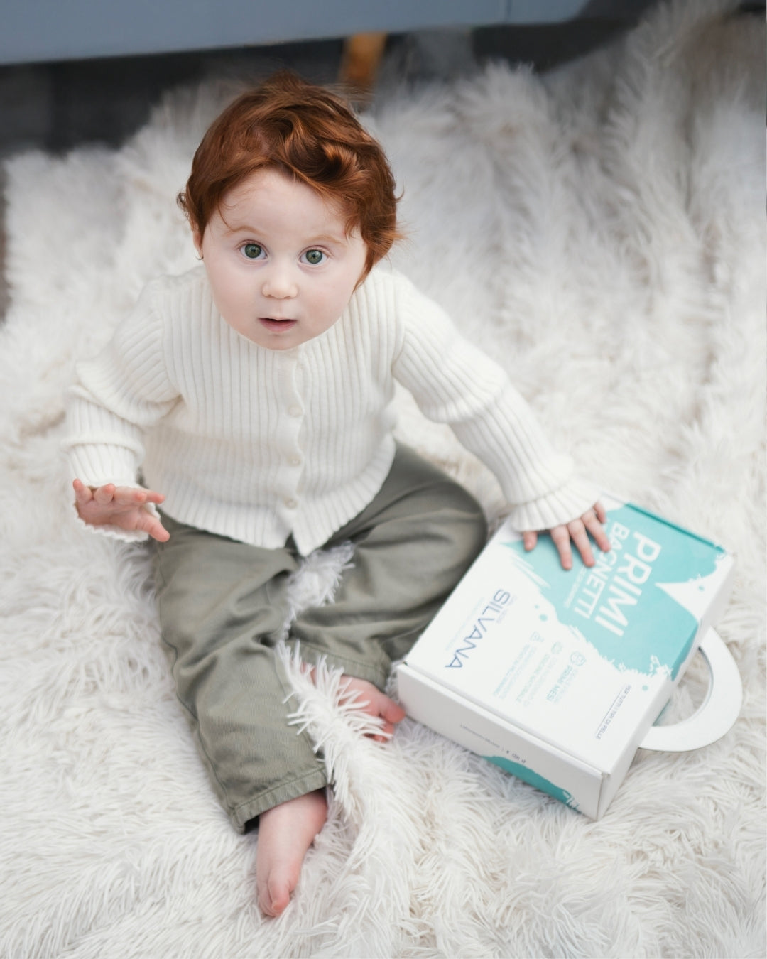 Bambino su tappeto con confezione Silvana Primi Bagnetti, cosmetici naturali bambini per pelli sensibili Made in Italy